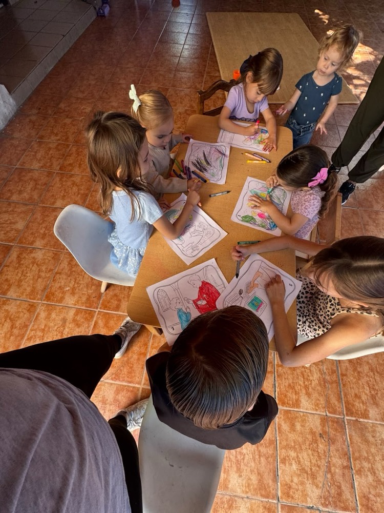 Un grupo de niños colorea las láminas de Santitos en una mesa